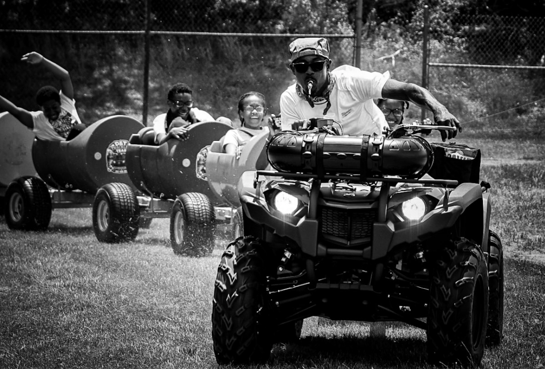 Black and white photo of ATV pulling children in train cars