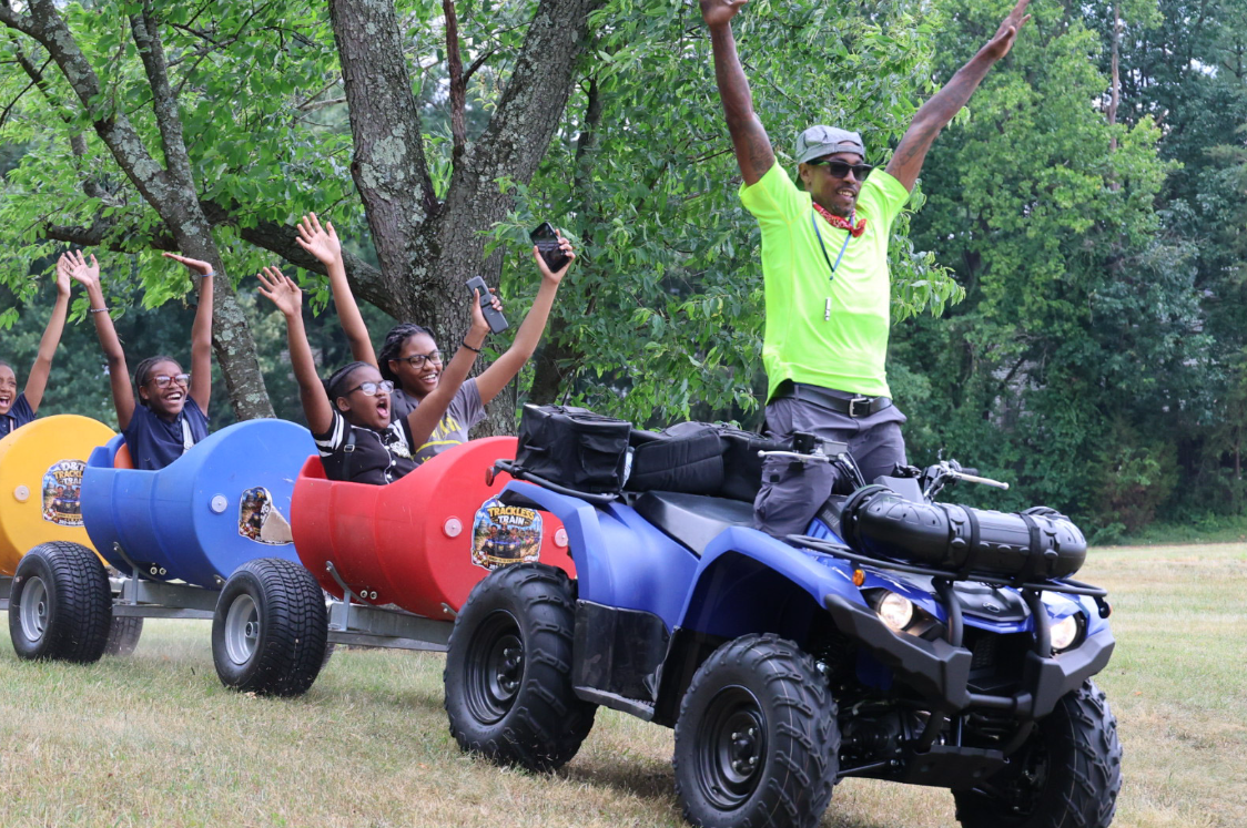 Train driver with arms raised celebrating with riders