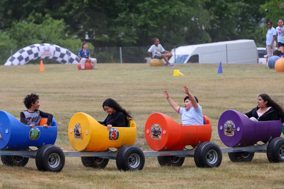 Riders enjoying colorful trackless train cars at an outdoor event